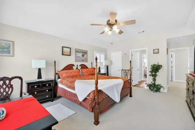 a bedroom with a bed couches lamps and a potted plant on the dresser