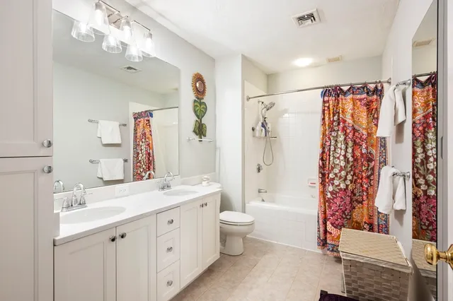 a spacious bathroom with a double vanity sink toilet mirror and shower