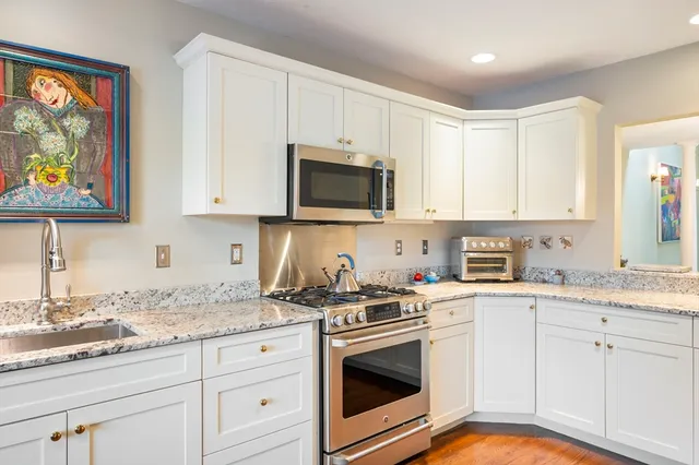 a kitchen with granite countertop white cabinets stainless steel appliances and a sink