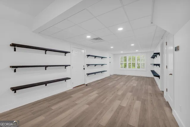 an empty room with wooden floor cabinet and windows