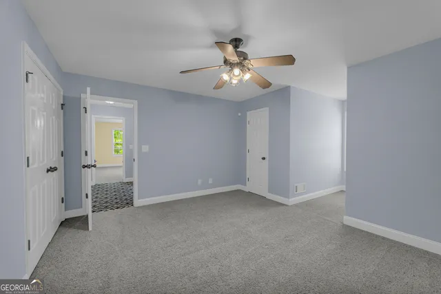 an empty room with a chandelier fan and windows