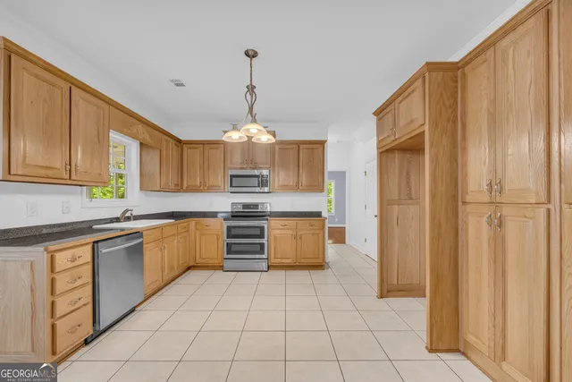 a large kitchen with stainless steel appliances granite countertop a stove a sink dishwasher and a refrigerator with wooden cabinets