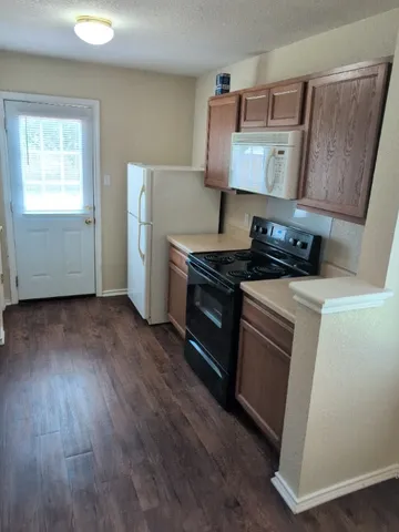 a kitchen with a stove and wooden floor