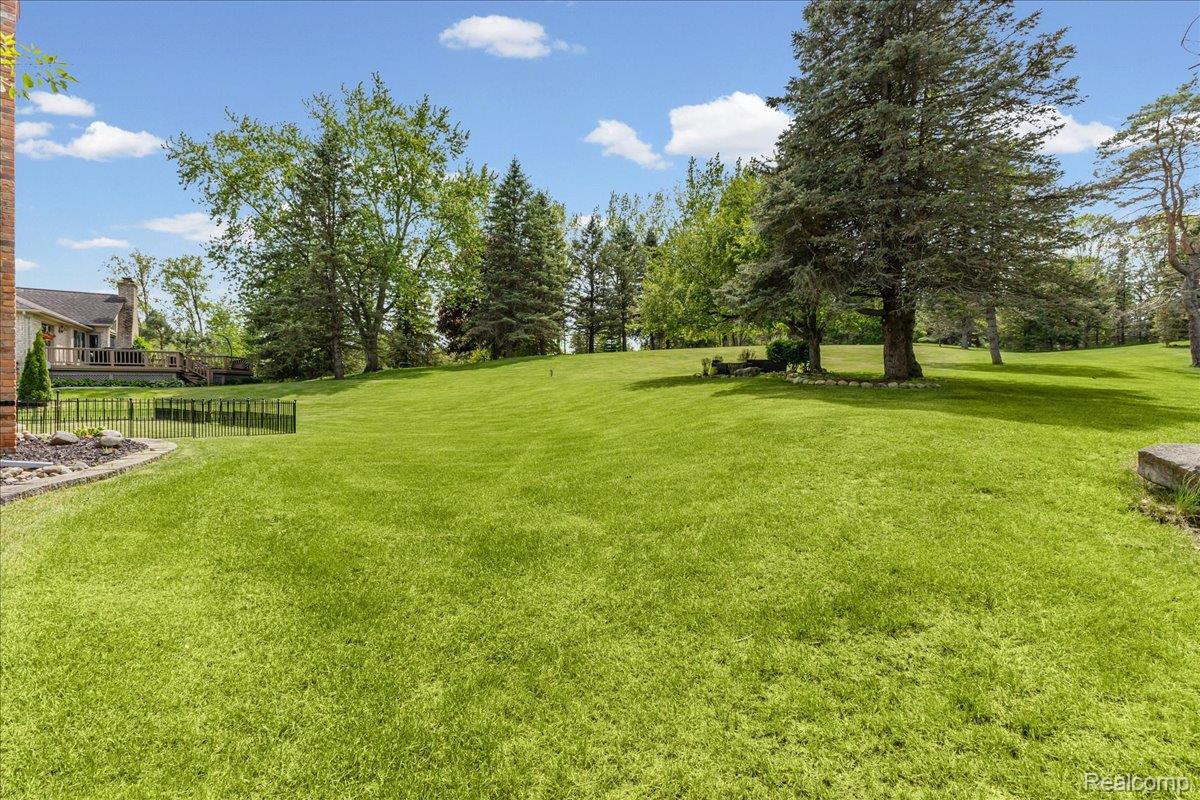 69075 Brookhill Drive Romeo, MI 48065 - Photo 24 of 28 Expansive green lawn with mature trees and a partial view of the property's exterior