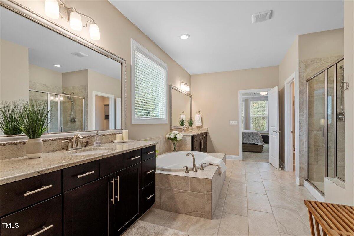 2421 Trenton Park Lane Raleigh, NC 27607 - Photo 38 of 66 a spacious bathroom with a granite countertop double vanity sink a mirror and a bathtub