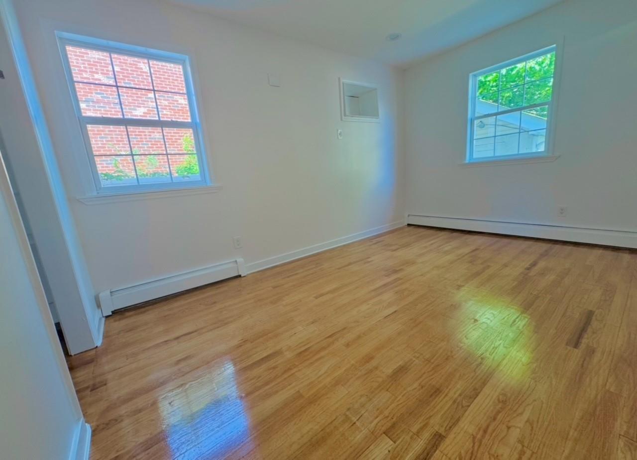 104-65 Springfield Boulevard Queens, NY 11429 - Photo 13 of 23 an empty room with wooden floor and windows