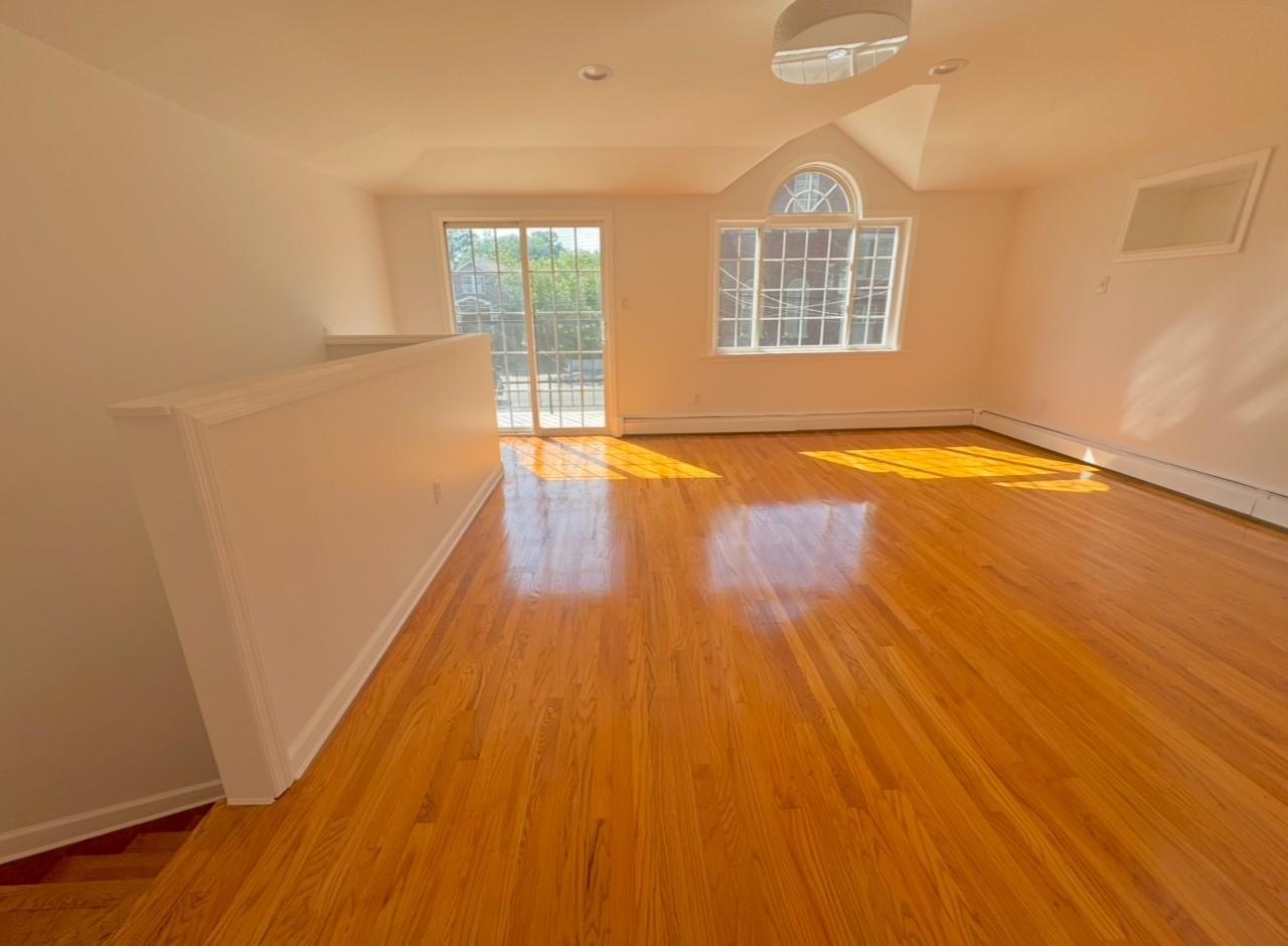 104-65 Springfield Boulevard Queens, NY 11429 - Photo 16 of 23 a view of an empty room with wooden floor and a window