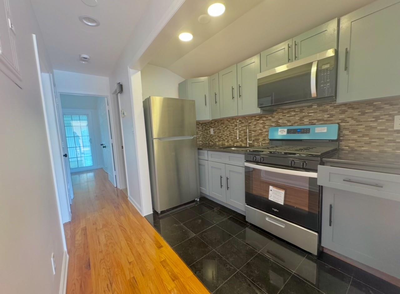 104-65 Springfield Boulevard Queens, NY 11429 - Photo 4 of 23 a kitchen with stainless steel appliances kitchen island granite countertop a stove a refrigerator and a sink
