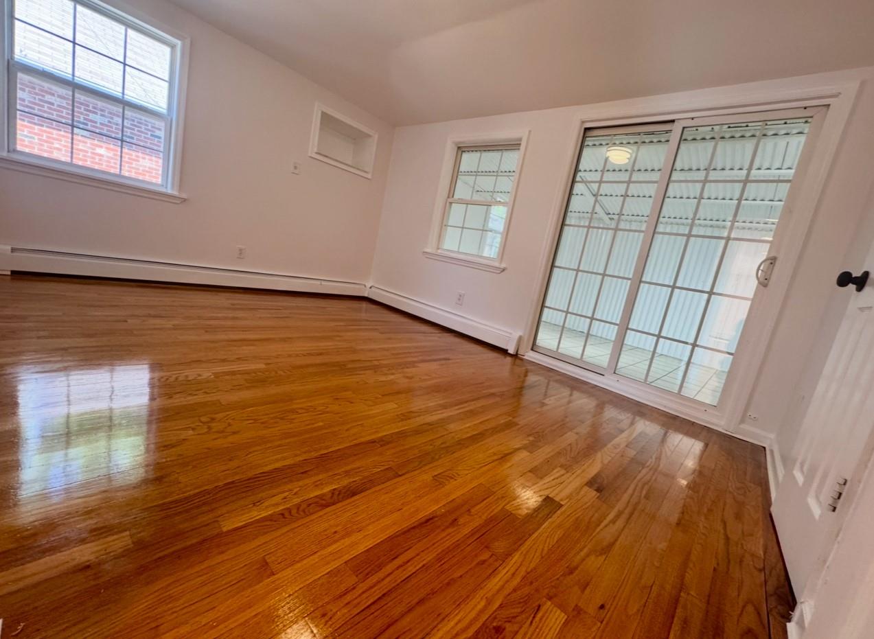 104-65 Springfield Boulevard Queens, NY 11429 - Photo 5 of 23 a view of an empty room with wooden floor and a window