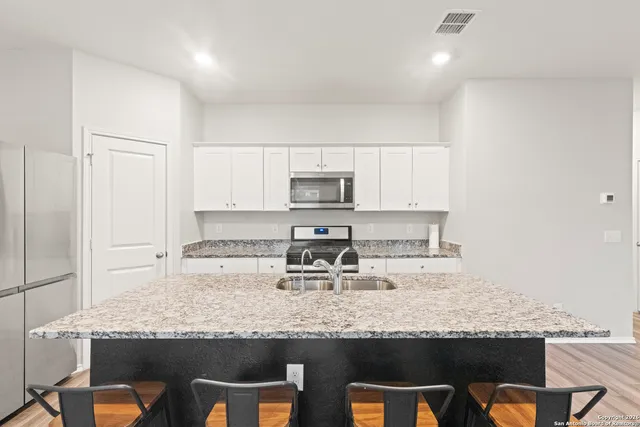 a kitchen with granite countertop a sink stainless steel appliances and white cabinets