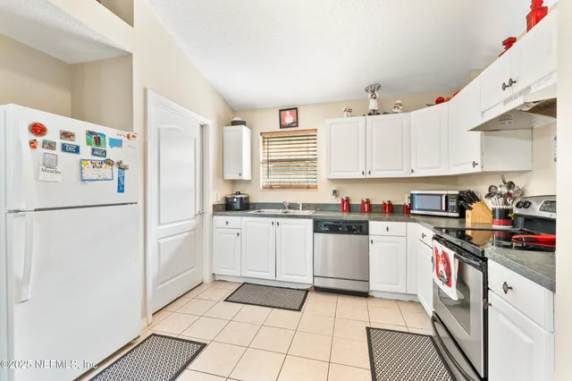 a kitchen with stainless steel appliances granite countertop a refrigerator sink and white cabinets