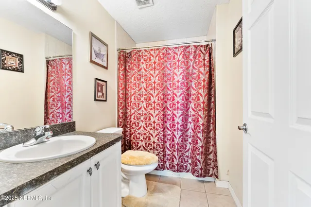 a bathroom with a granite countertop toilet sink and mirror