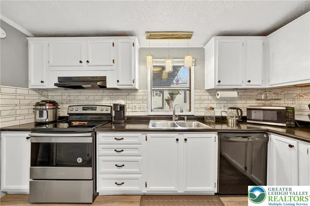 a kitchen with stainless steel appliances granite countertop a stove a sink and white cabinets