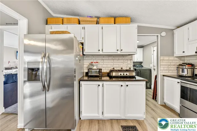 a kitchen with stainless steel appliances granite countertop a refrigerator a stove and white cabinets