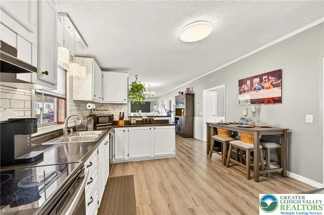 a kitchen with stainless steel appliances a stove a sink dishwasher and a dining table with wooden floor