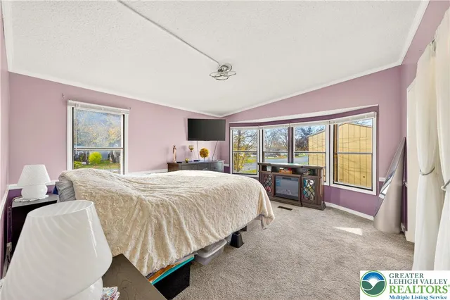 a bedroom with a bed and large windows