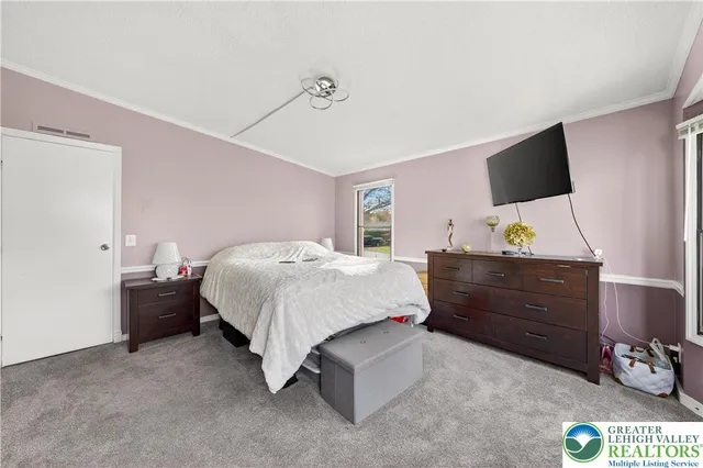 a bedroom with a bed and a flat tv screen on dresser