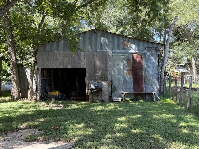 a view of a tiny house with yard and a tree