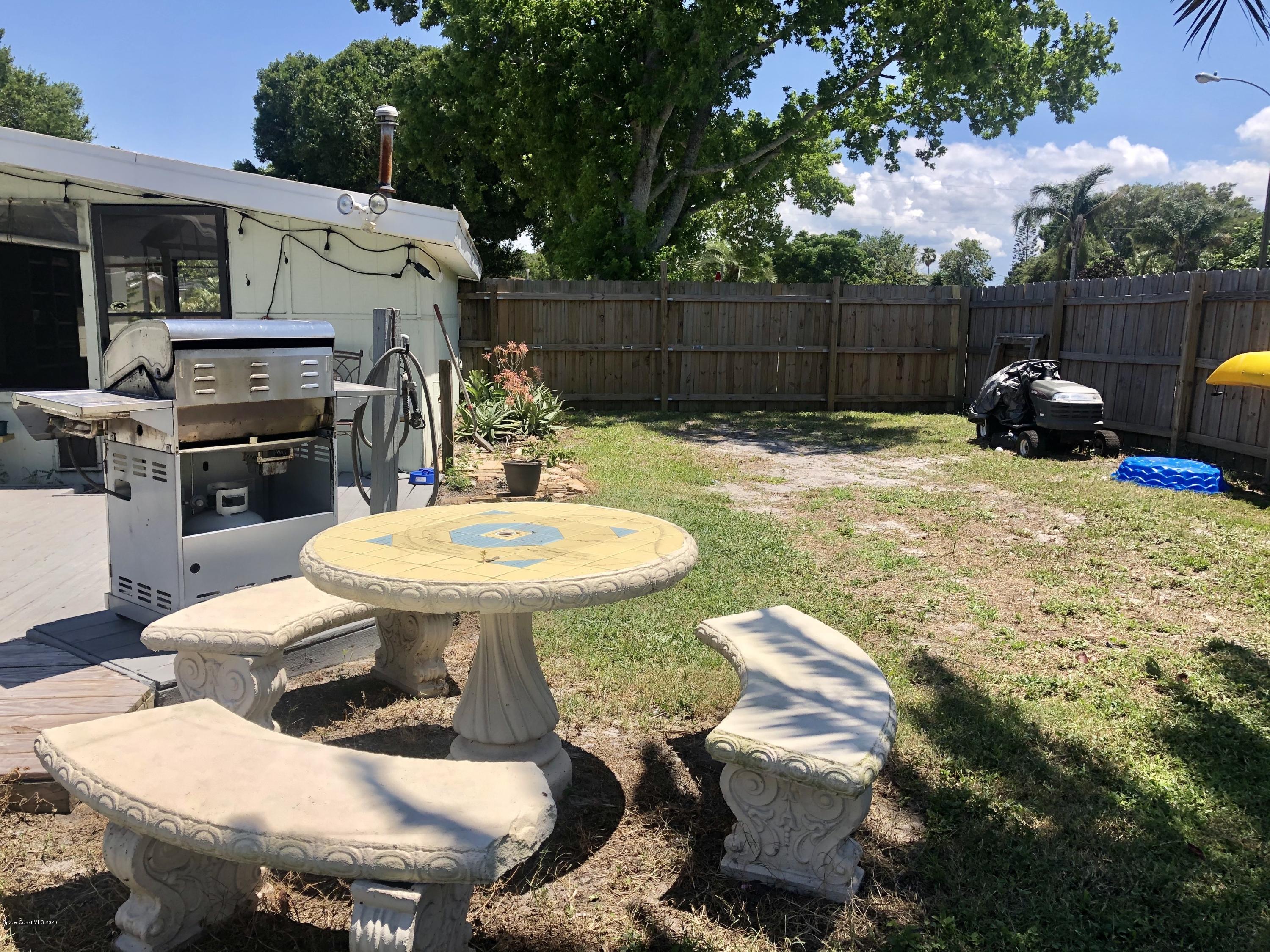 2224 Laden Road Melbourne, FL 32935 - Photo 24 of 26 a view of a backyard with table and chairs potted plants and wooden fence