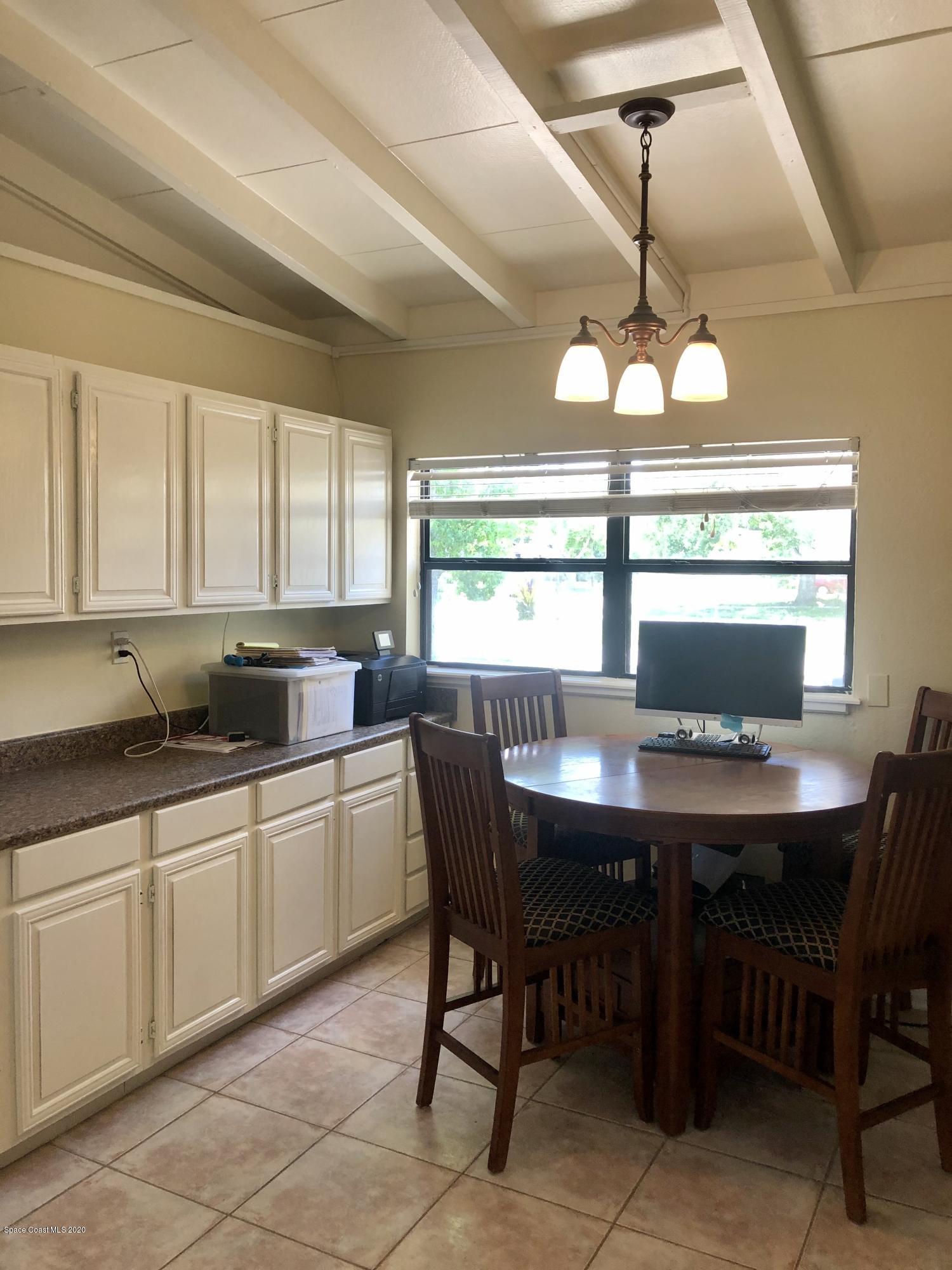 2224 Laden Road Melbourne, FL 32935 - Photo 4 of 26 a kitchen with a dining table chairs and white cabinets