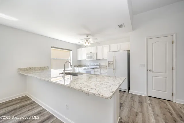 a kitchen with granite countertop white cabinets and refrigerator