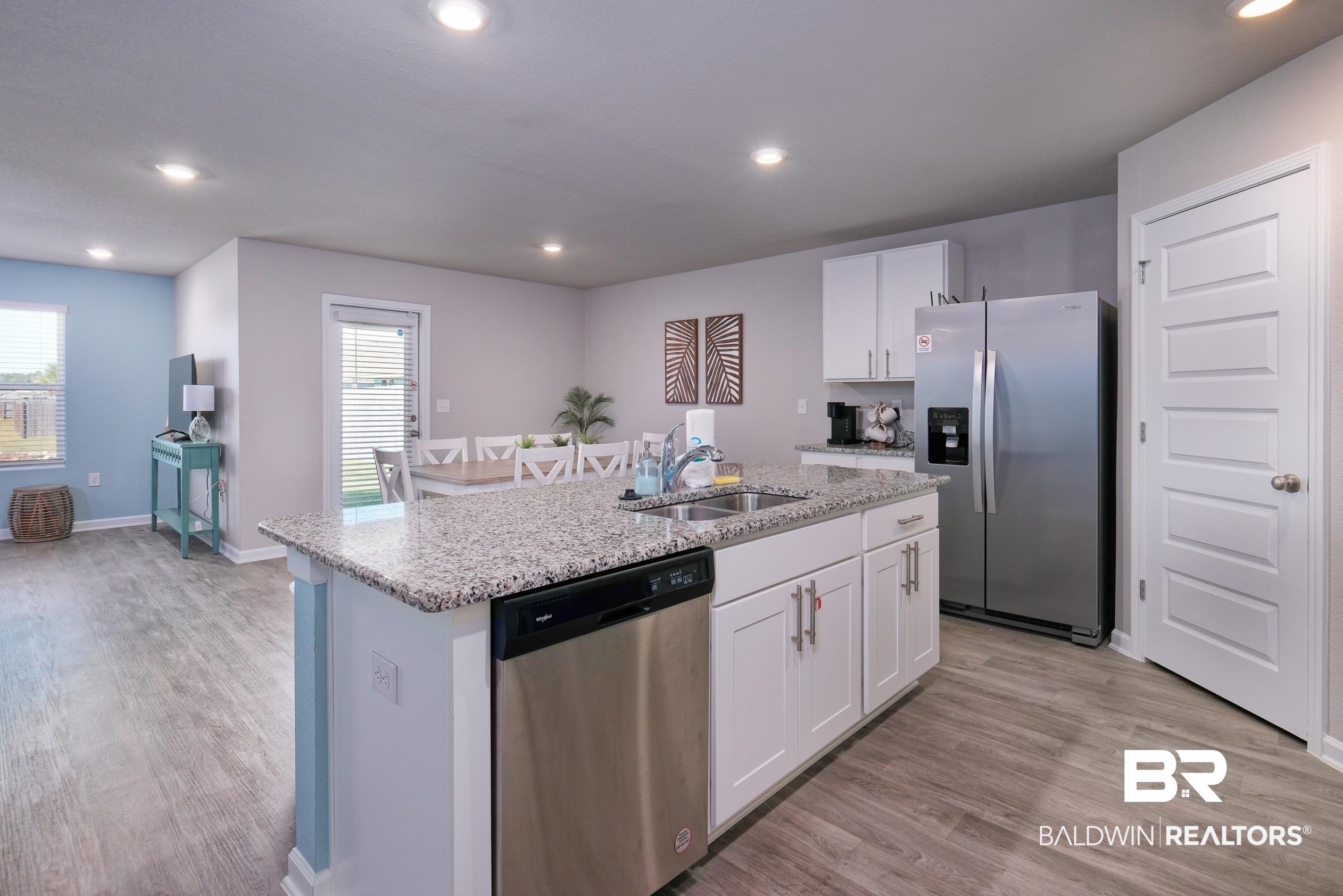 7425 Coppin Drive Foley, AL 36535 - Photo 6 of 41 Kitchen with appliances with stainless steel finishes, sink, light wood-type flooring, white cabinetry, and a kitchen island with sink