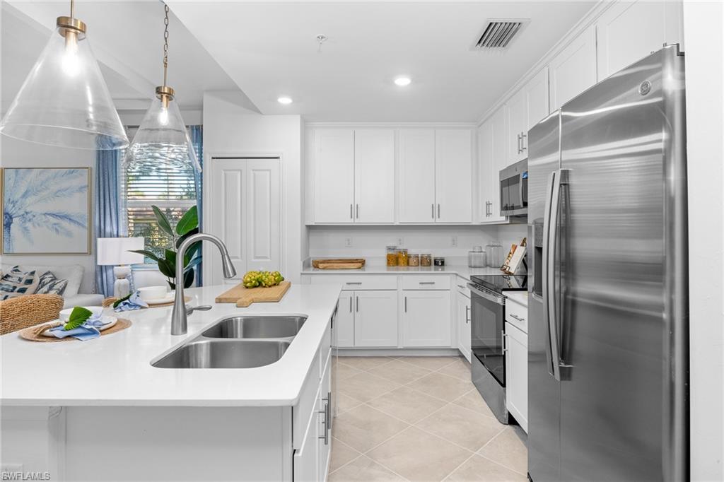 18461 Copperhead Drive, Unit 418 Lehigh Acres, FL 33936 - Photo 10 of 33 Kitchen featuring stainless steel appliances, light countertops, white cabinetry, light tile patterned floors, and recessed lighting