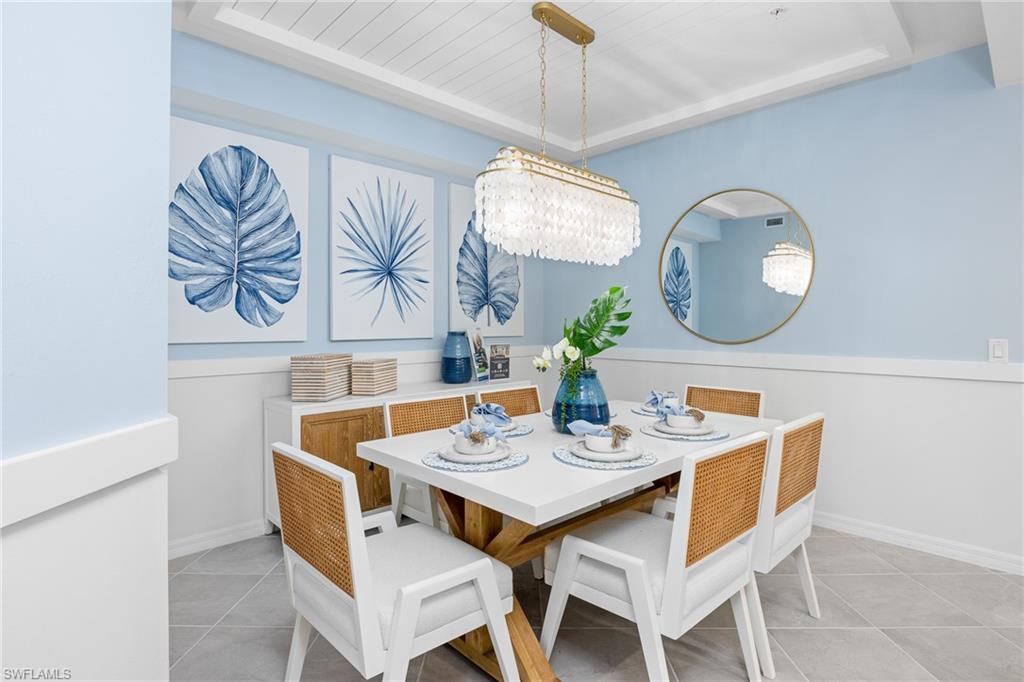 18461 Copperhead Drive, Unit 418 Lehigh Acres, FL 33936 - Photo 8 of 33 Dining space featuring a tray ceiling, light tile patterned floors, and a chandelier