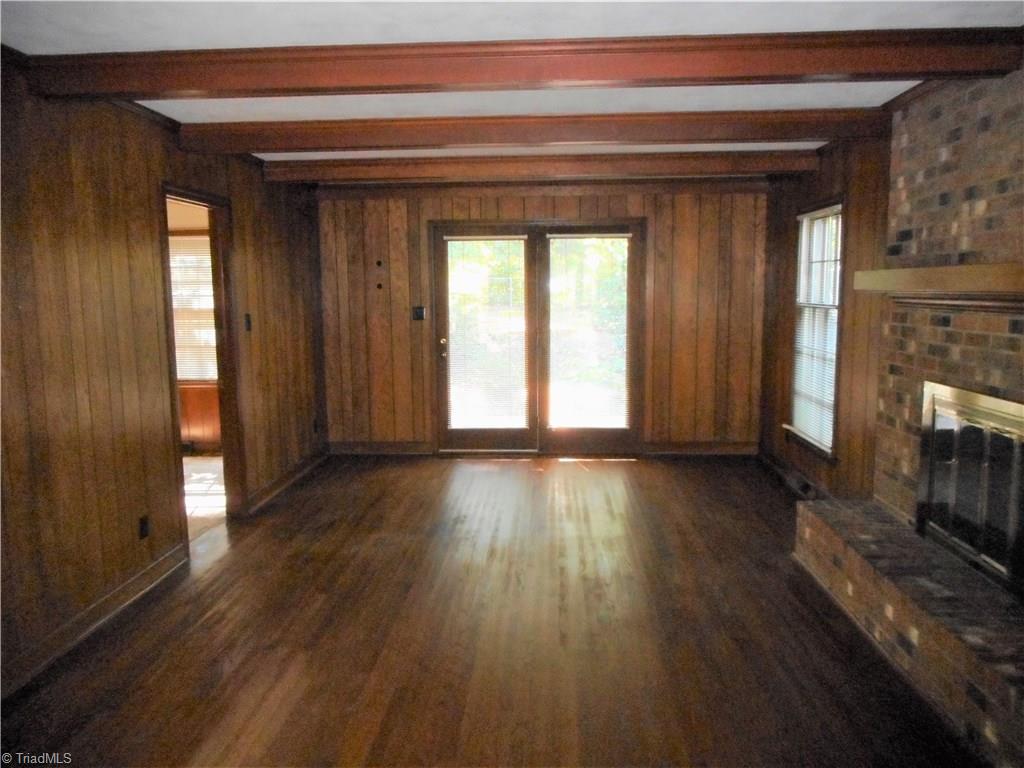 1607 Milan Road Greensboro, NC 27410 - Photo 5 of 22 Den offers cozy brick fireplace, exposed beams, wood floors and french doors to the patio.