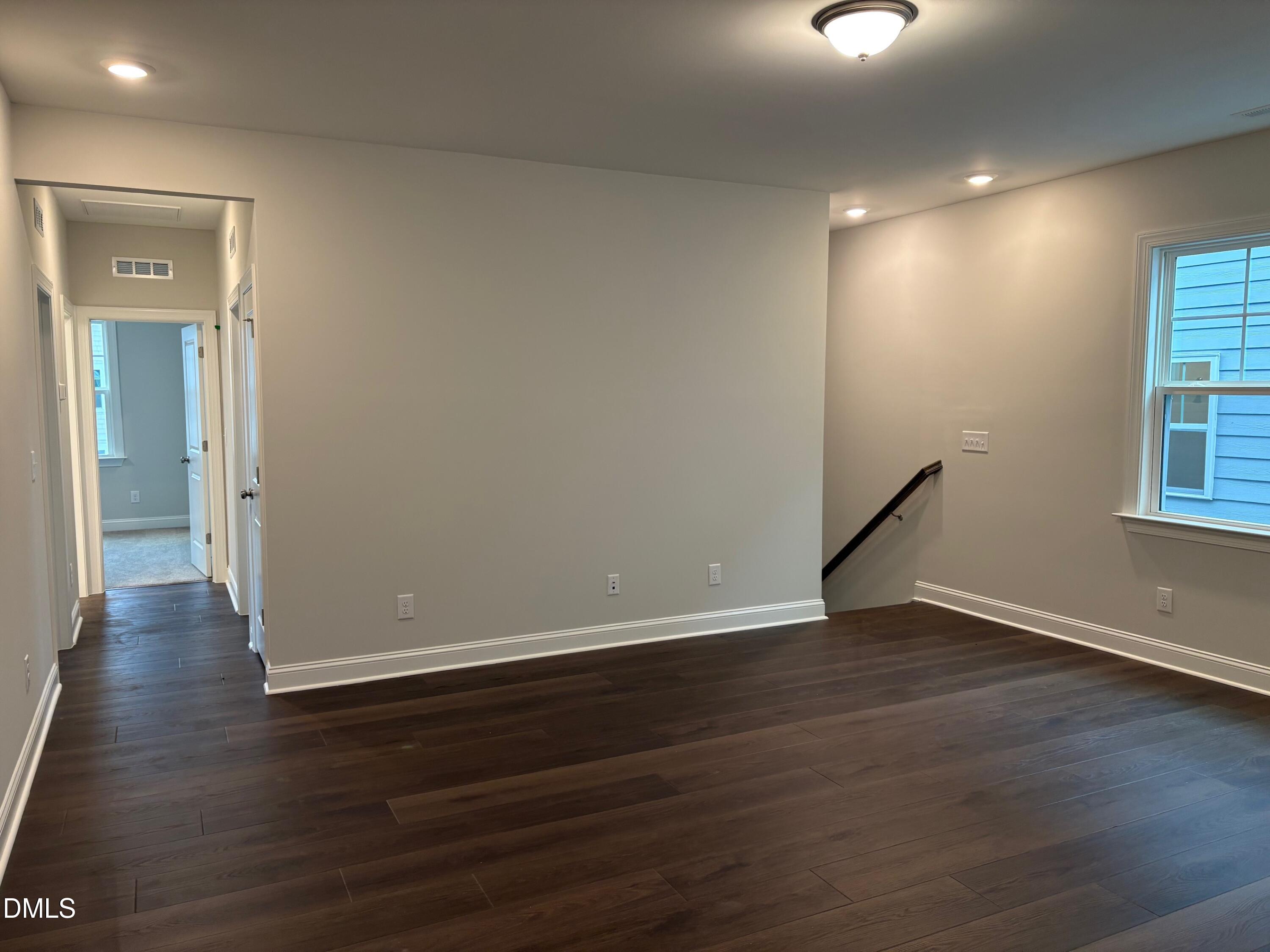 136 Corapeake Way Apex, NC 27539 - Photo 9 of 27 a view of an empty room with wooden floor and a window