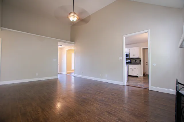 an empty room with wooden floor cabinet and windows