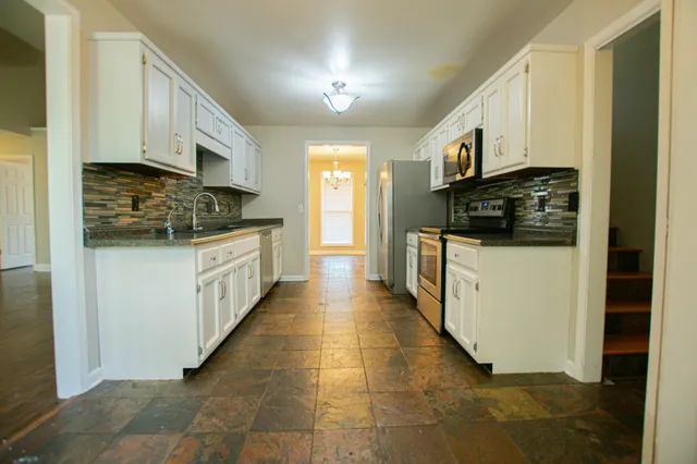 a kitchen with stainless steel appliances kitchen island granite countertop a stove top oven a sink a counter space and cabinets