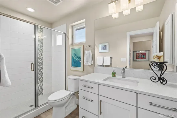 a bathroom with a toilet a sink a mirror a shower a vanity and window