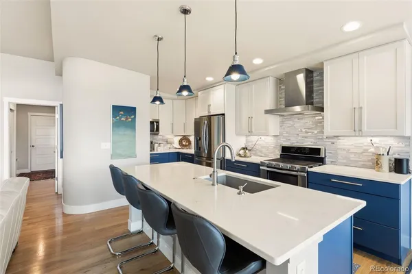 a kitchen with stainless steel appliances granite countertop a sink a stove a refrigerator a center island a stove and a cabinets