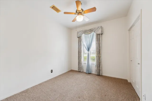 an empty room with windows and fan