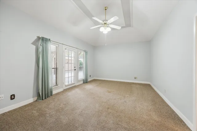 an empty room with chandelier fan and windows