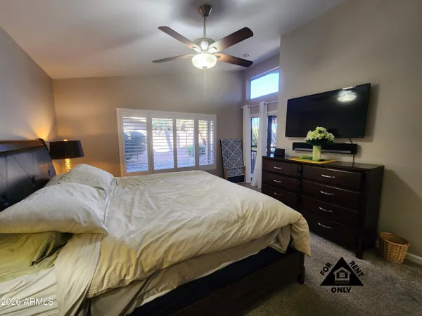 a bedroom with a bed and a flat tv screen on dresser
