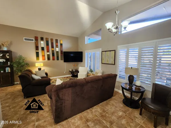a living room with furniture a chandelier and a flat screen tv