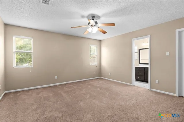 an empty room with windows and fan