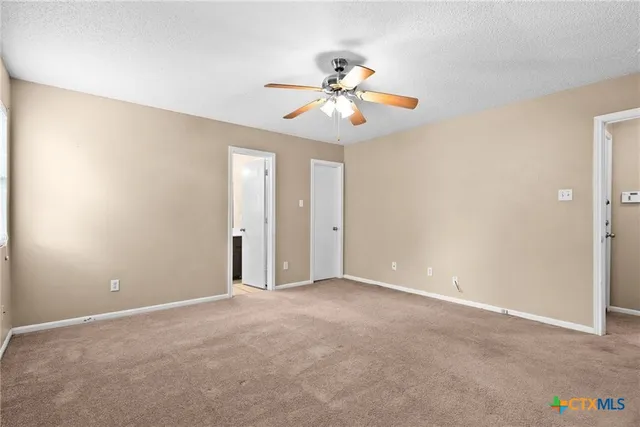 an empty room with a chandelier fan and windows