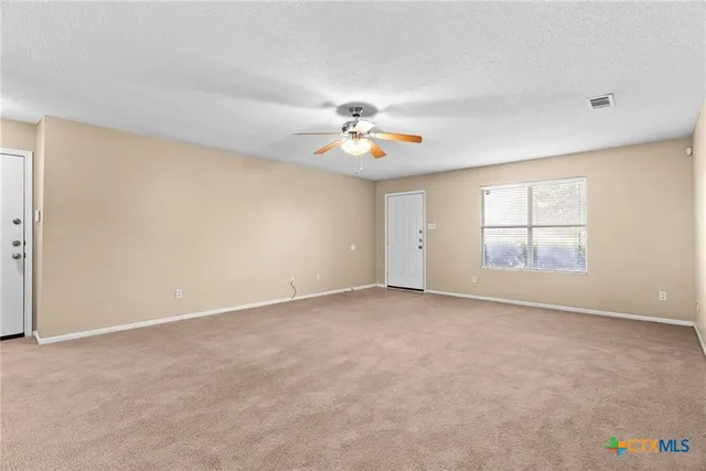 an empty room with windows and chandelier fan