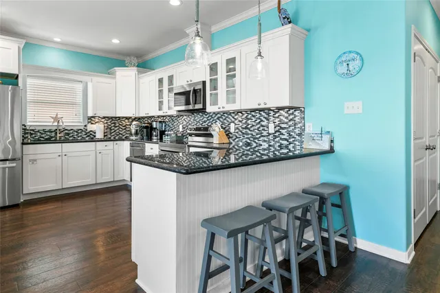 a kitchen with stainless steel appliances granite countertop a table chairs sink and cabinets