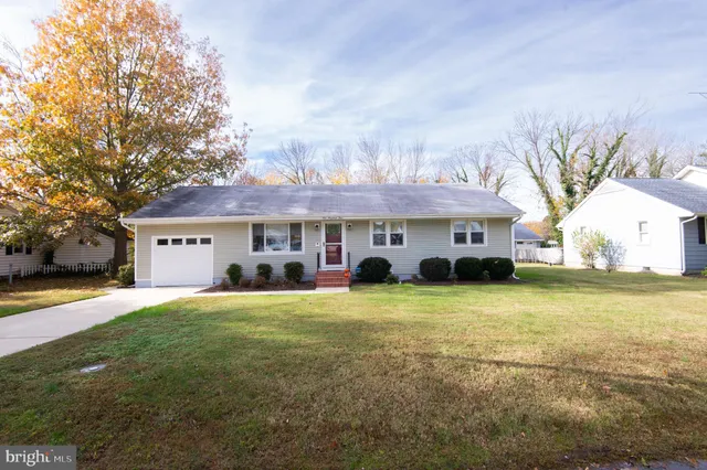 a front view of house with yard and trees in the background