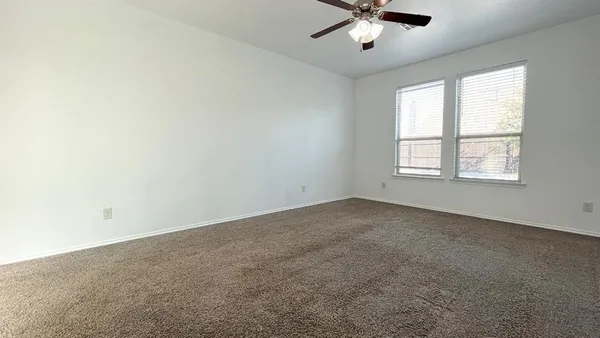 an empty room with a window and a ceiling fan