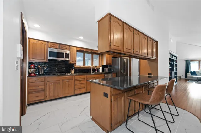 a kitchen with stainless steel appliances granite countertop a refrigerator a stove a sink dishwasher and white cabinets with wooden floor