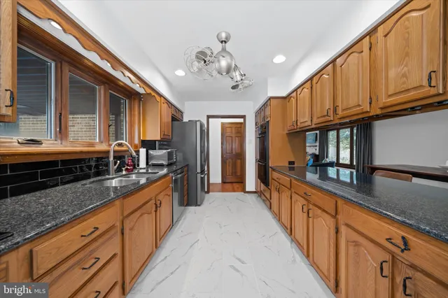 a large kitchen with stainless steel appliances granite countertop a lot of counter space and wooden floors