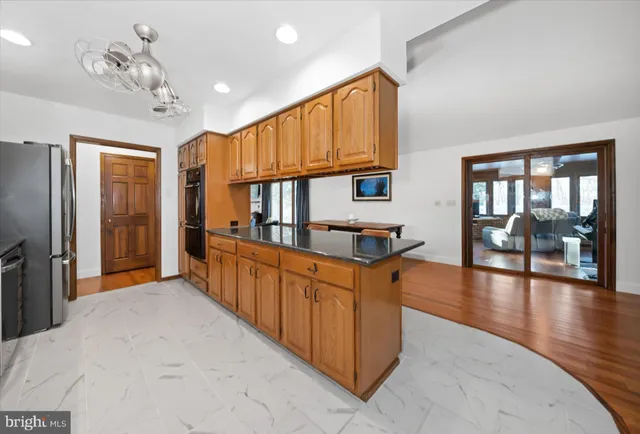 a kitchen with stainless steel appliances granite countertop a refrigerator a sink dishwasher a dining table and chairs with wooden floor