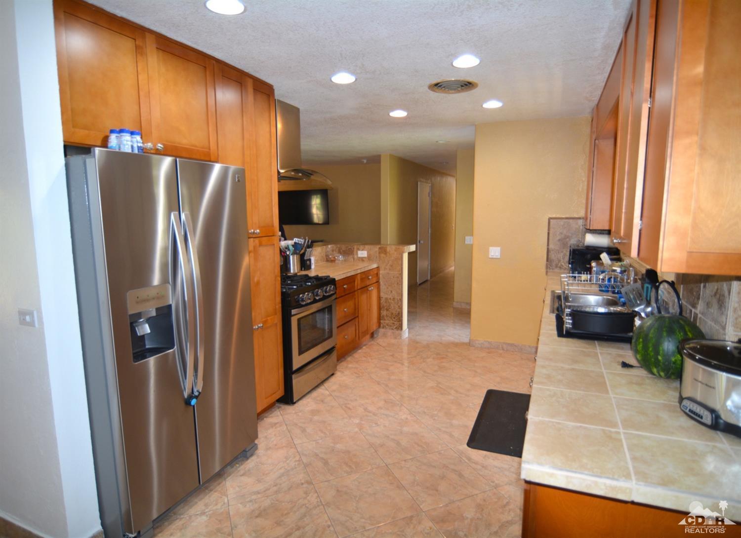 81256 Alberta Avenue Indio, CA 92201 - Photo 7 of 18 a kitchen with stainless steel appliances a refrigerator and wooden cabinets