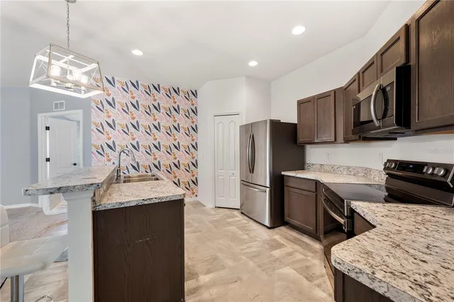 a kitchen with stainless steel appliances granite countertop a sink stove and refrigerator