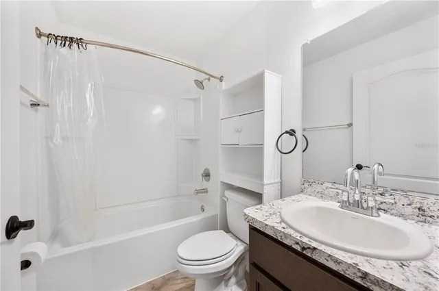 a bathroom with a granite countertop sink toilet mirror and shower
